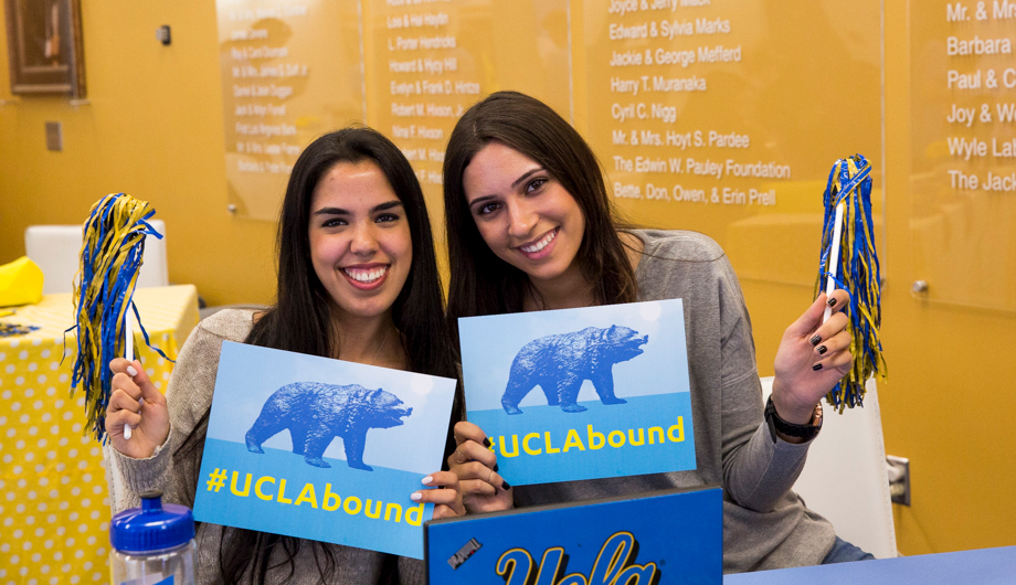 Two females smiling with UCLA Bound signs