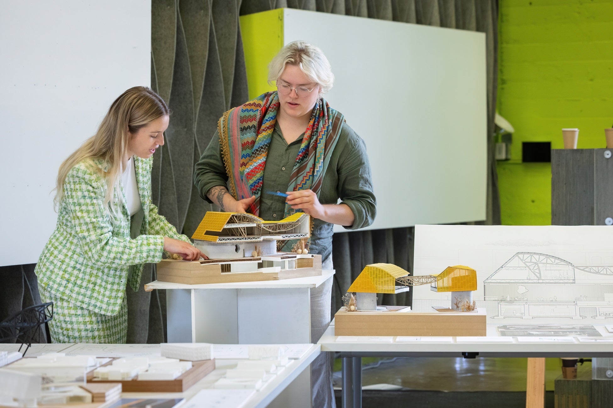 Two people prepare for a presentation with an architectural model in cross-section