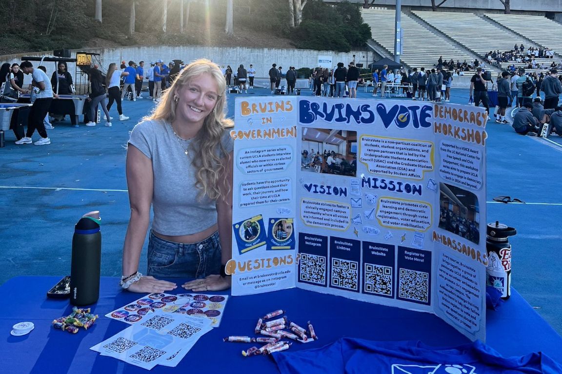 Student standing behind table with display board about voting