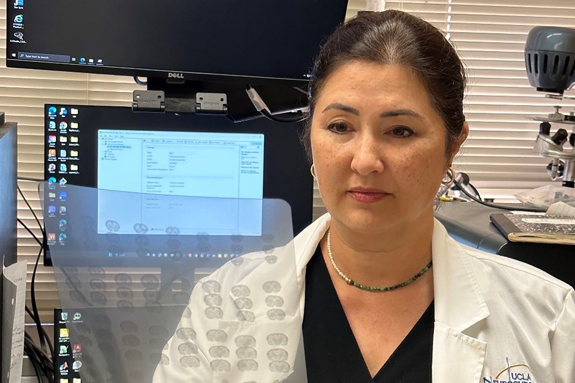 Woman with dark hair examines sheet of brain scans in lab