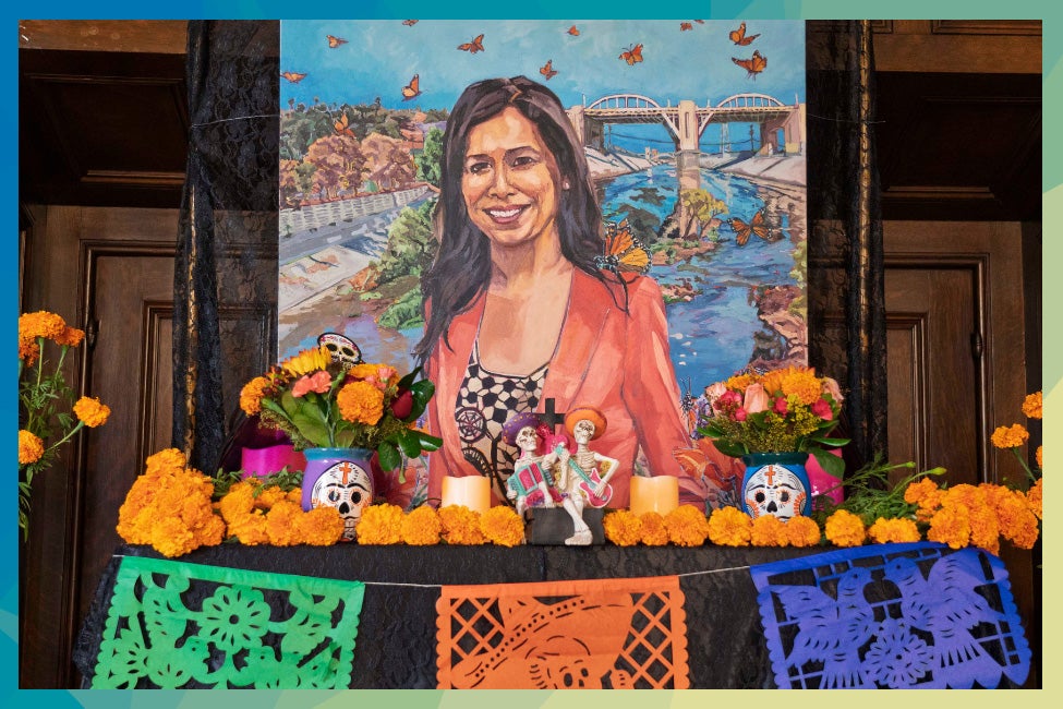 An ofrenda (home altar) with a portrait of Cindy Montanez adorned with a monarch butterfly on her shoulder, alongside marigolds and other the vibrant and colorful Day of the Dead decor