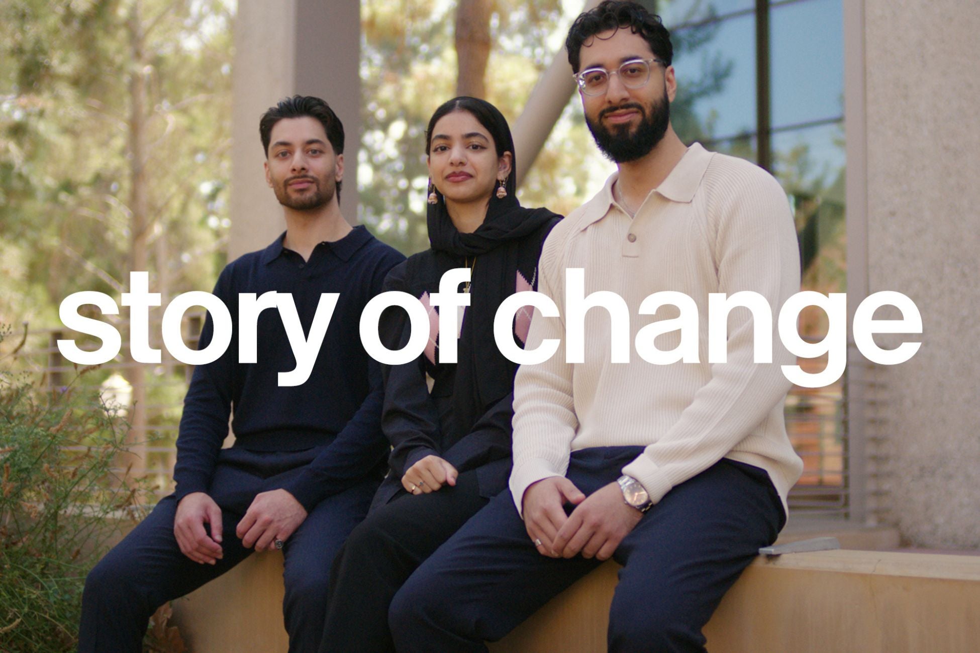 Three young adults sit together outdoors, looking confident and engaged. The text ‘story of change’ overlays the image.