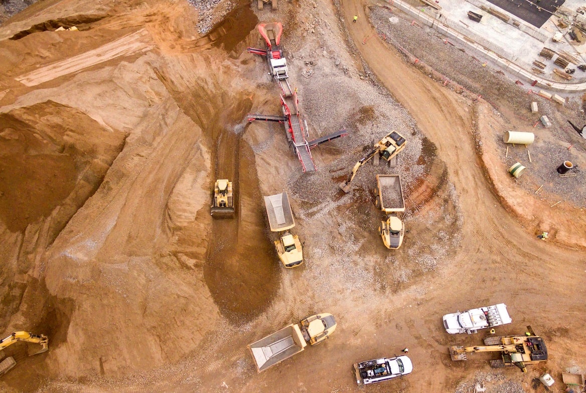 Construction vehicles shape the land for building.