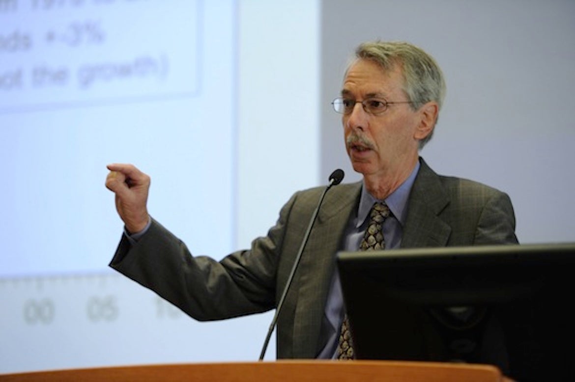 Ed Leamer, in suit and tie, gestures while speaking at a podium