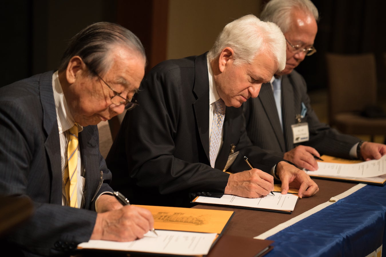 Chancellor Block (center) at table signing papers opening of the UCLA Japan Center in Tokyo, flanked by Masaru Murai (left) and Tomohiro Tohyama (right), in June 2016